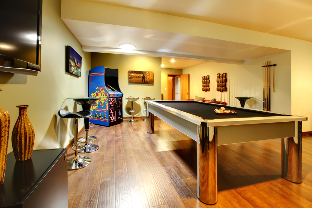 Fun play room home interior. Basement room without windows with pool table, TV, games.